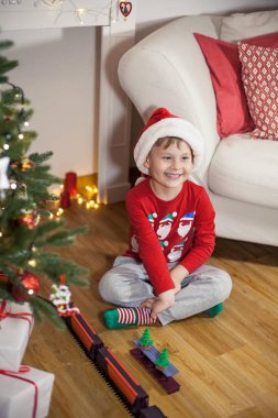 Noel ağacı yakınındaki bir Noel Baba şapkalı bir mutlu 4 yaşındaki çocuk portresi. Noel. Tatil. Yeni yıl. Mutluluk. Çocuk. Rahat.