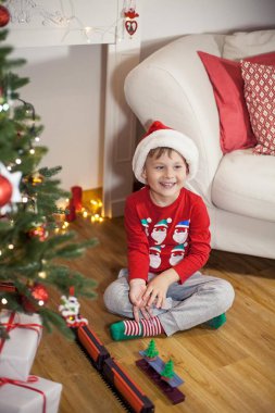 Noel ağacı yakınındaki bir Noel Baba şapkalı bir mutlu 4 yaşındaki çocuk portresi. Noel. Tatil. Yeni yıl. Mutluluk. Çocuk. Rahat.