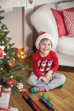 Noel ağacı yakınındaki bir Noel Baba şapkalı bir mutlu 4 yaşındaki çocuk portresi. Noel. Tatil. Yeni yıl. Mutluluk. Çocuk. Rahat.