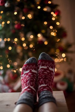 Yakın çekim. Yılbaşı çoraplı kadın ayak Noel ağacı yakınındaki. Tatil. Rahat.