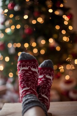 Yakın çekim. Yılbaşı çoraplı kadın ayak Noel ağacı yakınındaki. Tatil. Rahat.