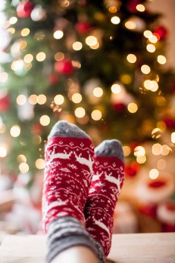 Yakın çekim. Yılbaşı çoraplı kadın ayak Noel ağacı yakınındaki. Tatil. Rahat.