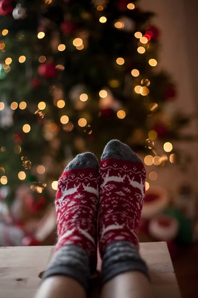 Yakın çekim. Yılbaşı çoraplı kadın ayak Noel ağacı yakınındaki. Tatil. Rahat.