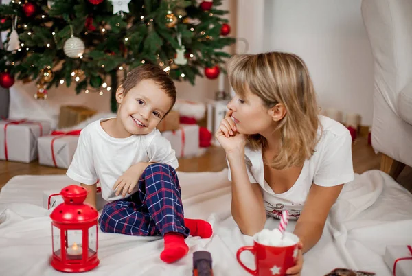 한 젊은 어머니와 아들이 크리스마스 트리 근처 연주. 크리스마스 파자마에 가족입니다. 크리스마스 마음이 편 함. 휴일입니다. 아늑한. — 스톡 사진