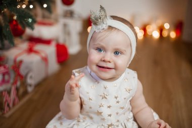 Noel ağacı yanında küçük bebek. Şirin mavi gözlü bebek başında bir taç ile bir altın elbiseli. Mutluluk. Tatil. Noel. Yeni yıl. Rahat.