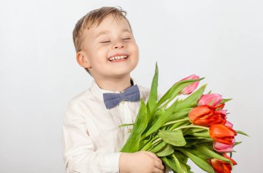 Bir buket çiçek tutan şirin ufaklık. Lale. Anneler günü. Uluslararası Kadınlar Günü. Mutlu bir çocuğun portresi