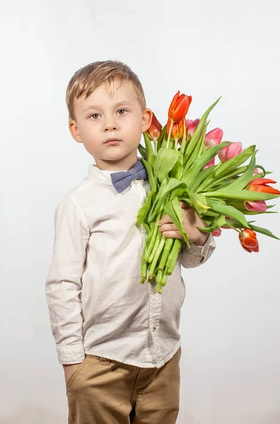Milý chlapeček drží kytici květin. Tulipány. Den matek. Mezinárodní den Dámské. Portrét šťastný malého chlapce na — Stock fotografie