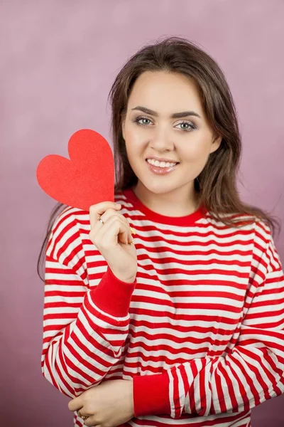 Jeune belle femme tenant un cœur. Portrait d'une fille sur fond rose. Saint Valentin. L'amour . — Photo