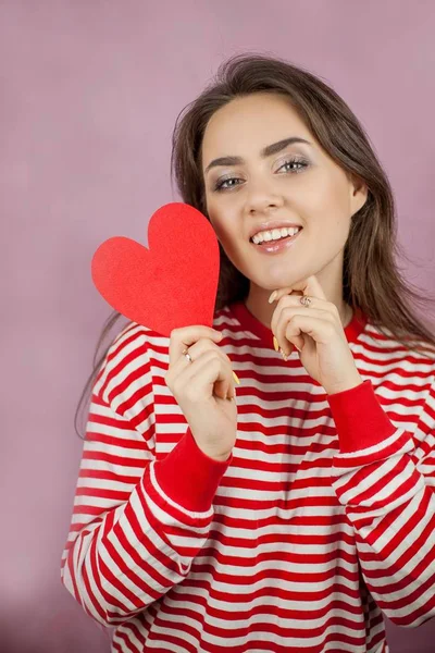 Jeune belle femme tenant un cœur. Portrait d'une fille sur fond rose. Saint Valentin. L'amour . — Photo