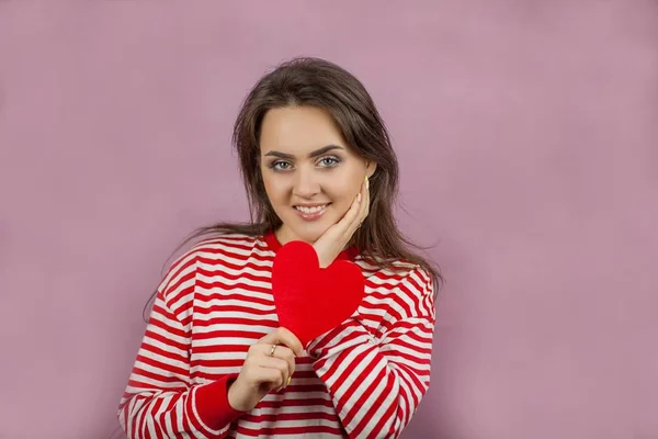 Jeune belle femme tenant un cœur. Portrait d'une fille sur fond rose. Saint Valentin. L'amour . — Photo