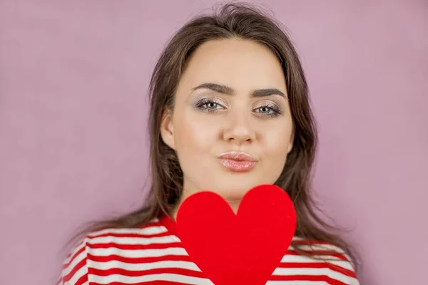 Jeune belle femme tenant un cœur. Portrait d'une fille sur fond rose. Saint Valentin. L'amour . — Photo