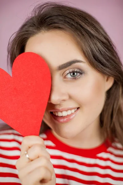 Jeune belle femme tenant un cœur. Portrait d'une fille sur fond rose. Saint Valentin. L'amour . — Photo