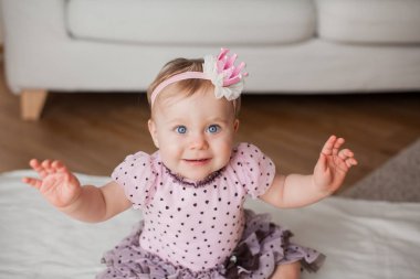 Küçük şirin mavi gözlü kız başında bir taç ile pembe elbiseli. Evde bebek portresi. Mutluluk. Rahat. Doğum günü. Bahar.