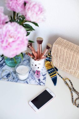 Peonies. Buket pembe peonies, mum, hasır çanta, eşarp, parfüm, takı, beyaz masa kozmetik masada telefon