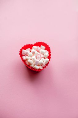 Marshmallow pembe bir arka plan üzerinde kırmızı kalp şekli. Sevgililer günü. Aşk.