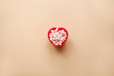 Marshmallow bej renkli arka plan üzerinde kırmızı kalp şekli. Sevgililer günü. Aşk.