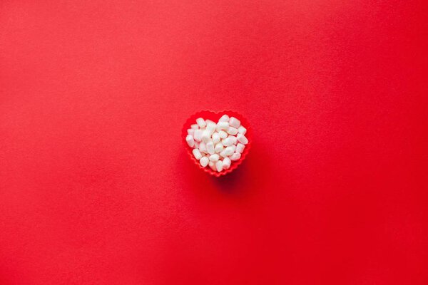 Red heart shape with marshmallows on a red background. Valentine's Day. Love.