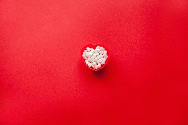 Red heart shape with marshmallows on a red background. Valentine's Day. Love.
