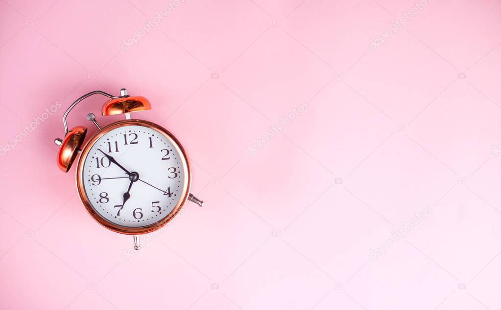 Alarm clock on a pink background.