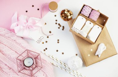 Bahar dekor. Pembe bir kurdele, pırıltılar, kurdeleler, bir mum, bir defter pembe ve beyaz arka plan üzerinde beyaz hediye kutusu. Anneler günü.