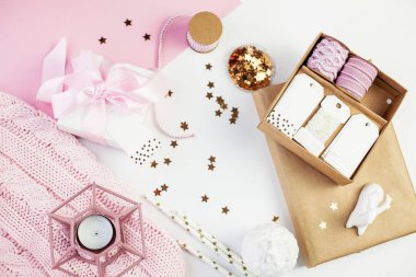 Bahar dekor. Pembe bir kurdele, pırıltılar, kurdeleler, bir mum, bir defter pembe ve beyaz arka plan üzerinde beyaz hediye kutusu. Anneler günü.