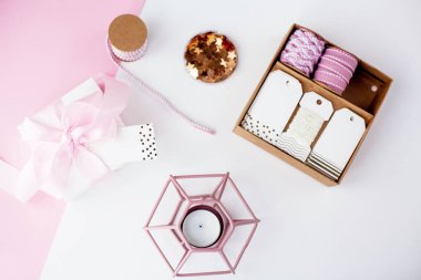 Bahar dekor. Pembe bir kurdele, pırıltılar, kurdeleler, bir mum pembe ve beyaz arka plan üzerinde beyaz hediye kutusu. Anneler günü.