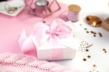 Bahar dekor. Pembe bir kurdele, pırıltılar, kurdeleler, bir mum, takı, pembe ve beyaz arka plan üzerinde bir not defteri ile beyaz hediye kutusu. Anneler günü.