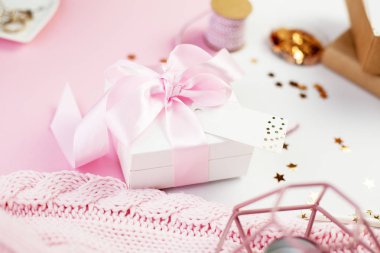 Bahar dekor. Pembe bir kurdele, pırıltılar, kurdeleler, bir mum, takı, pembe ve beyaz arka plan üzerinde bir not defteri ile beyaz hediye kutusu. Anneler günü.