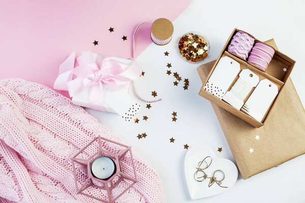 Весенний декор. Белая подарочная коробка с розовой лентой, блестками, лентами, свечкой, украшениями, блокнотом на розовом и белом фоне. День матери
.