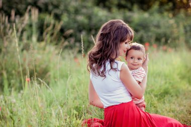 Güzel bir aile haşhaş alanına yürüyor. Küçük oğlu olan genç bir anne yürüyor. Yaz. Bahar.