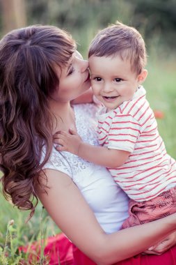 Güzel bir aile haşhaş alanına yürüyor. Küçük oğlu olan genç bir anne yürüyor. Yaz. Bahar.