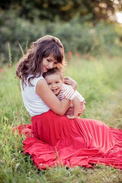 Güzel bir aile haşhaş alanına yürüyor. Küçük oğlu olan genç bir anne yürüyor. Yaz. Bahar.
