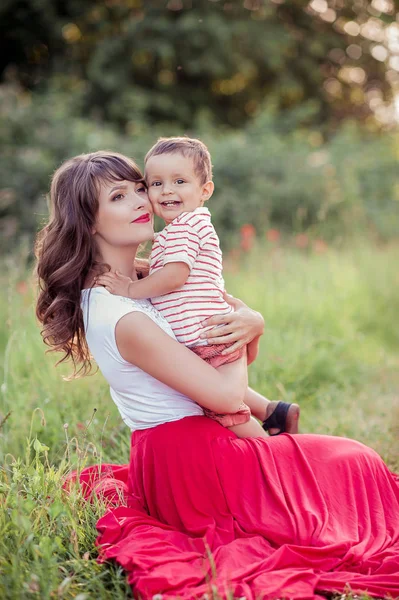 Güzel bir aile haşhaş alanına yürüyor. Küçük oğlu olan genç bir anne yürüyor. Yaz. Bahar.