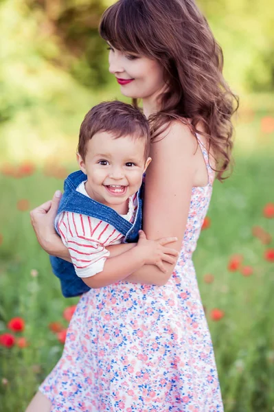 A beautiful family is walking in a poppy field. A young mother with a little son is walking. Summer. Spring. — Stock Photo, Image