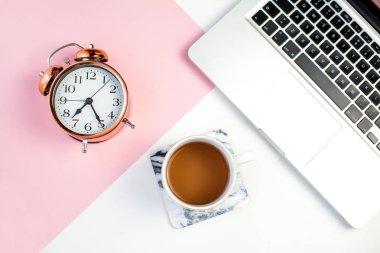 Çalar saat, çay, beyaz pembe bir arka plan üstünde laptop. Bahar.