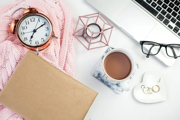 Spring decor. Womens clothing. Alarm clock, gift box with a pink ribbon, jewelry, a candle, a mug of tea, glasses, a notebook on a white background.