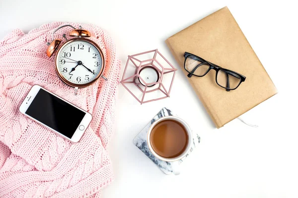 Spring decor. Women's clothing. Alarm clock, candle, tea mug, glasses, notebook on a white background. Spring.