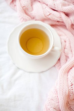 Güzel beyaz fincan çay yatakta, pembe örgü şal ile. Yatakta kahvaltı. Sabah. Bahar.
