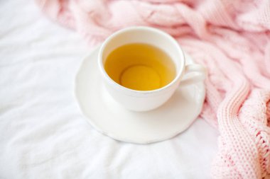 Güzel beyaz fincan çay yatakta, pembe örgü şal ile. Yatakta kahvaltı. Sabah. Bahar.