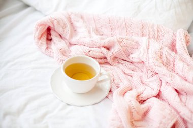 Güzel beyaz fincan çay yatakta, pembe örgü şal ile. Yatakta kahvaltı. Sabah. Bahar.