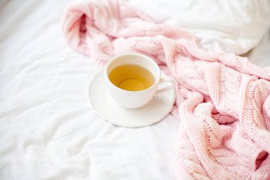 Güzel beyaz fincan çay yatakta, pembe örgü şal ile. Yatakta kahvaltı. Sabah. Bahar.