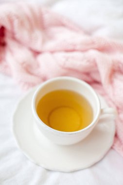Güzel beyaz fincan çay yatakta, pembe örgü şal ile. Yatakta kahvaltı. Sabah. Bahar.