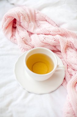 Güzel beyaz fincan çay yatakta, pembe örgü şal ile. Yatakta kahvaltı. Sabah. Bahar.