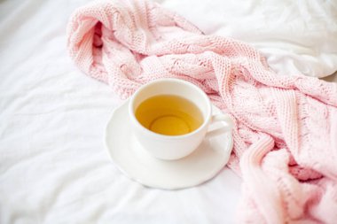 Güzel beyaz fincan çay yatakta, pembe örgü şal ile. Yatakta kahvaltı. Sabah. Bahar.