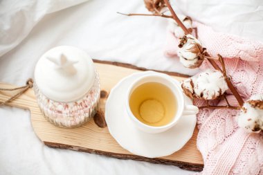 Çay ile beyaz kupa, yatağın üstüne güzel bir kavanoza marshmallow. Yatakta kahvaltı. Rahat. Pembe kareli. Pamuk.