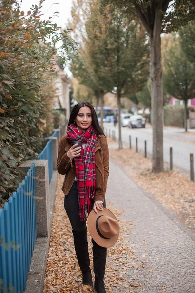 Une belle jeune femme marchant dans une ville européenne tient un chapeau dans ses mains et boit du café. Le printemps. Automne. Portrait d'une jeune femme . — Photo