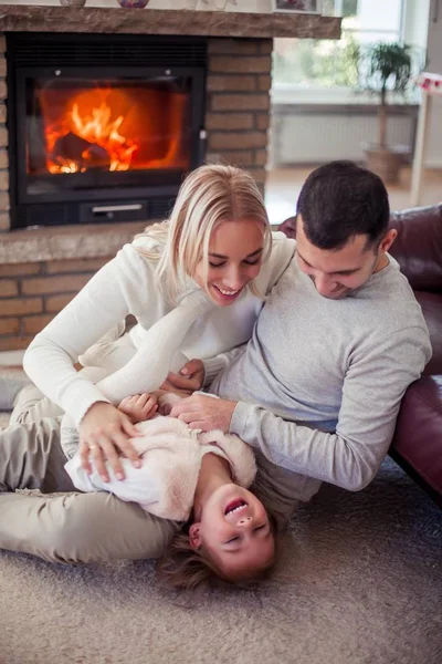 La famille est assise sur le canapé près de la cheminée. Maman, papa, fille à l'intérieur de la maison. Confortable . — Photo