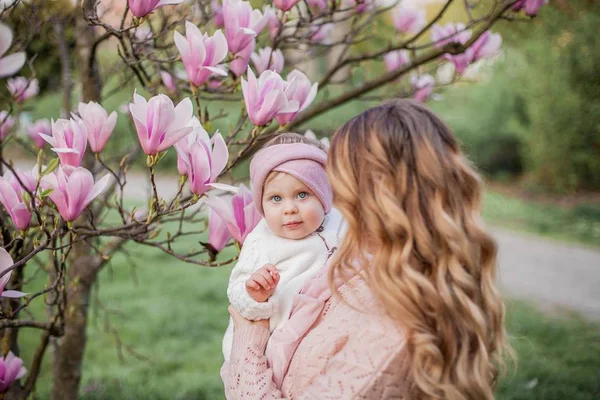 Mooie jonge moeder en kleine dochter in de buurt van de Magnolia. Lente familieportret. — Stockfoto