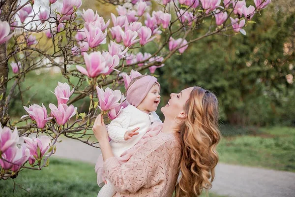 Beautiful young mother and little daughter near the magnolia. Spring family portrait. — Stock Photo, Image
