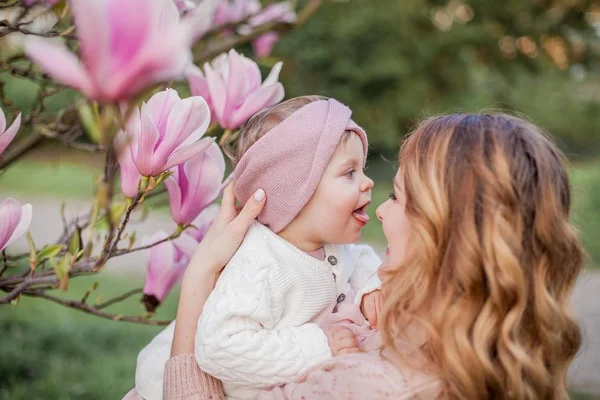 Beautiful young mother and little daughter near the magnolia. Spring family portrait. — Stock Photo, Image